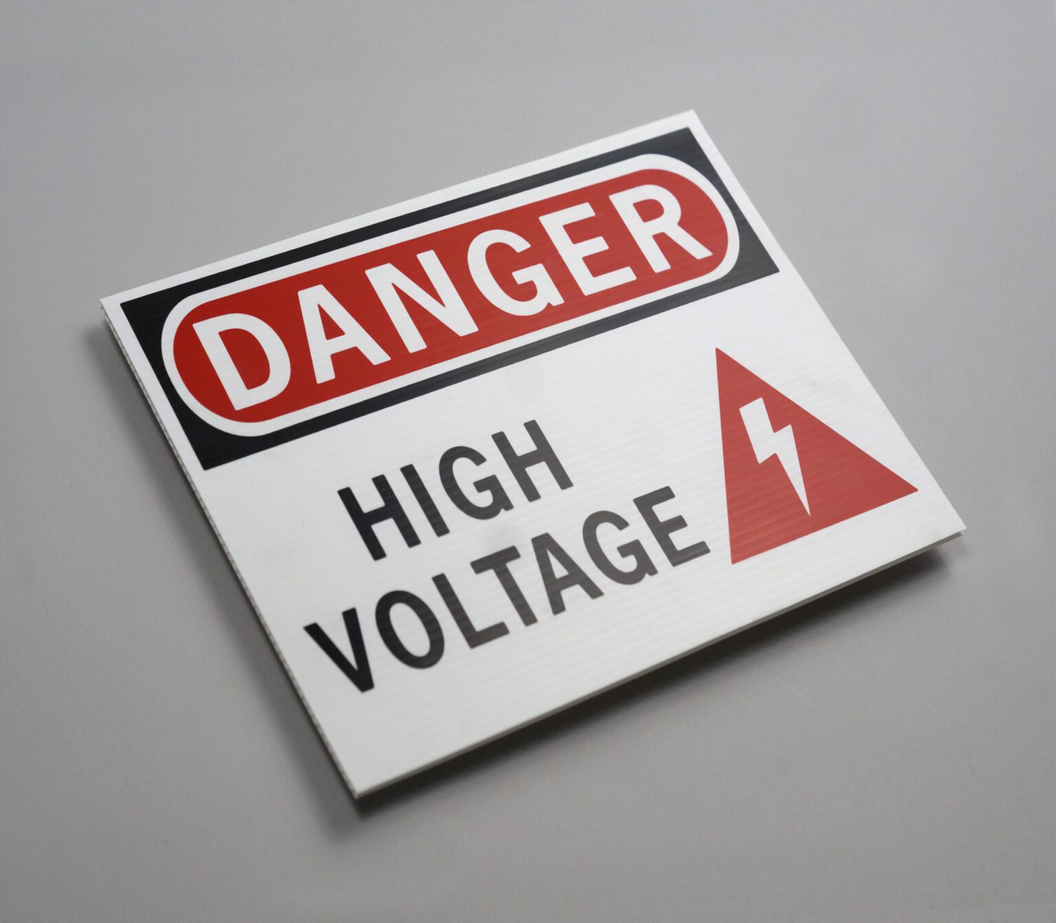 A white red and black high voltage sign that reads "danger high voltage"
