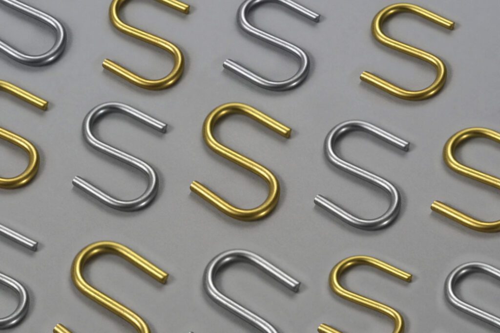 Silver and gold s-hooks are neatly Laid down Against a clean gray background
